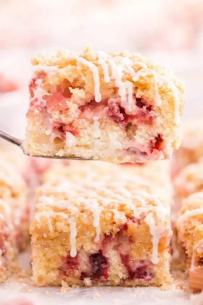 Strawberry rhubarb cake slice with crumb topping and vanilla glaze