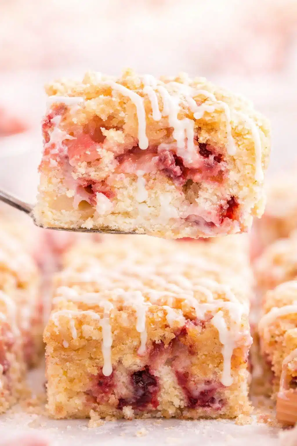 Strawberry rhubarb cake slice with crumb topping and vanilla glaze