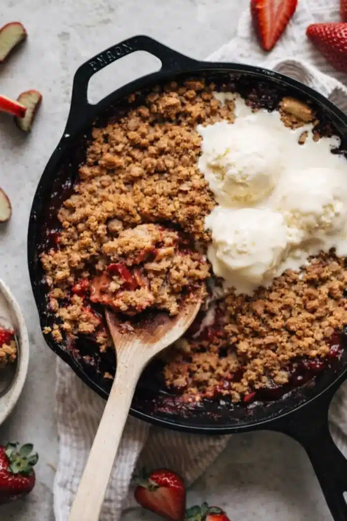 Strawberry rhubarb crisp with oat topping and vanilla ice cream in a baking dish