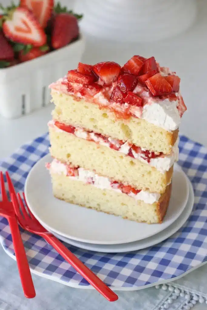 Slice of Strawberry Shortcake Cake with whipped cream and fresh strawberry layers