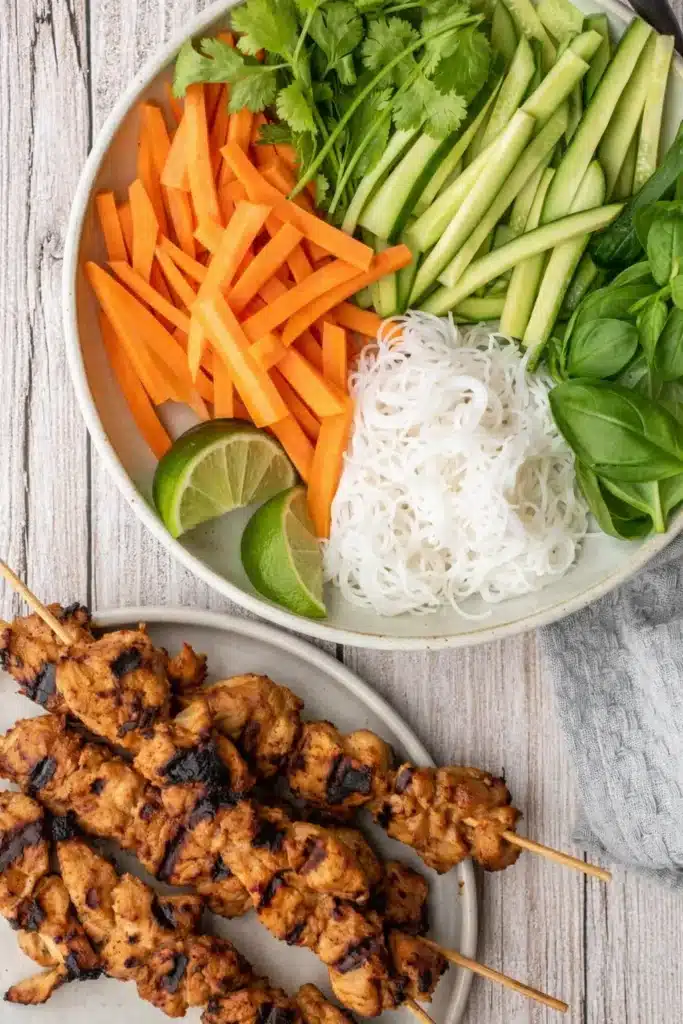 Vietnamese Summer Rolls ingredients with noodles, vegetables, herbs, and grilled chicken