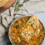 Winter minestrone soup with beans, vegetables, and crusty bread in rustic bowl