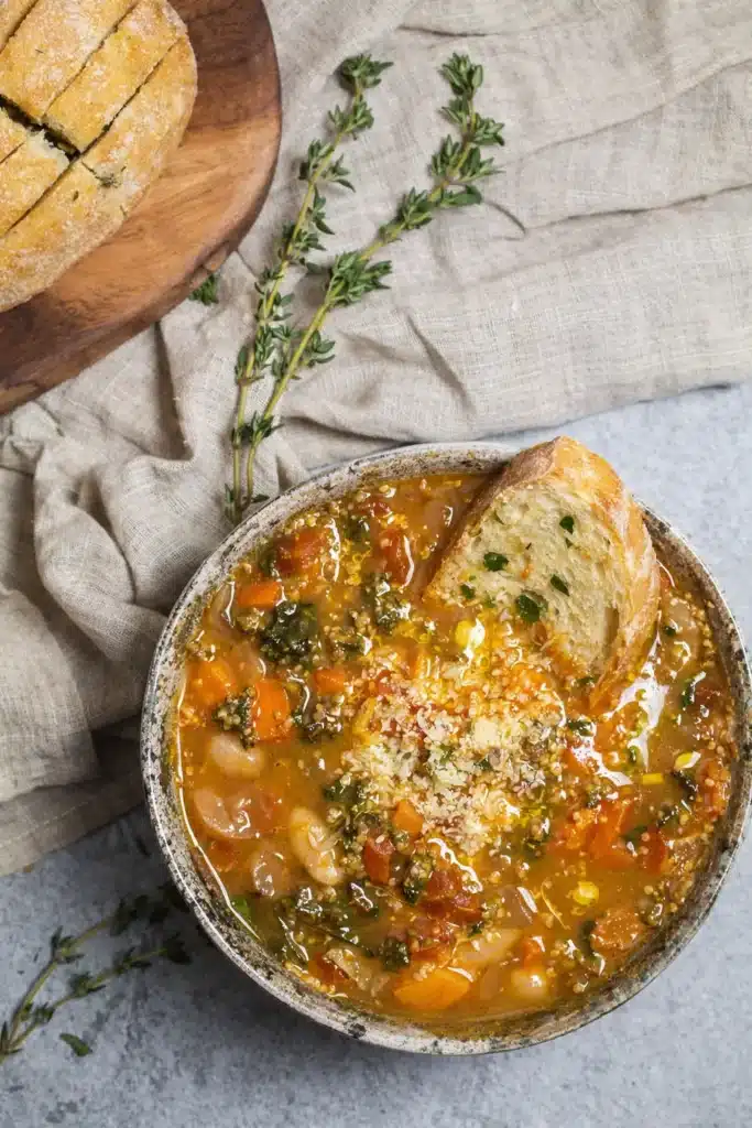 Winter minestrone soup with beans, vegetables, and crusty bread in rustic bowl