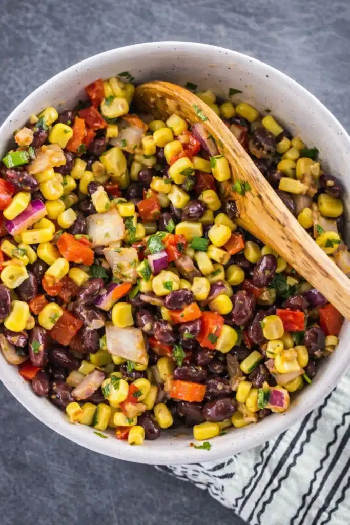 black bean and corn salsa with wooden spoon in ceramic bowl