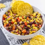 Black bean and corn salsa with tortilla chips in a rustic bowl on a wooden table