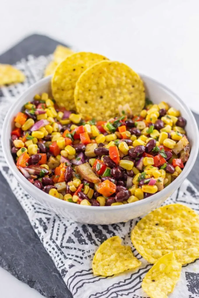 Black bean and corn salsa with tortilla chips in a rustic bowl on a wooden table