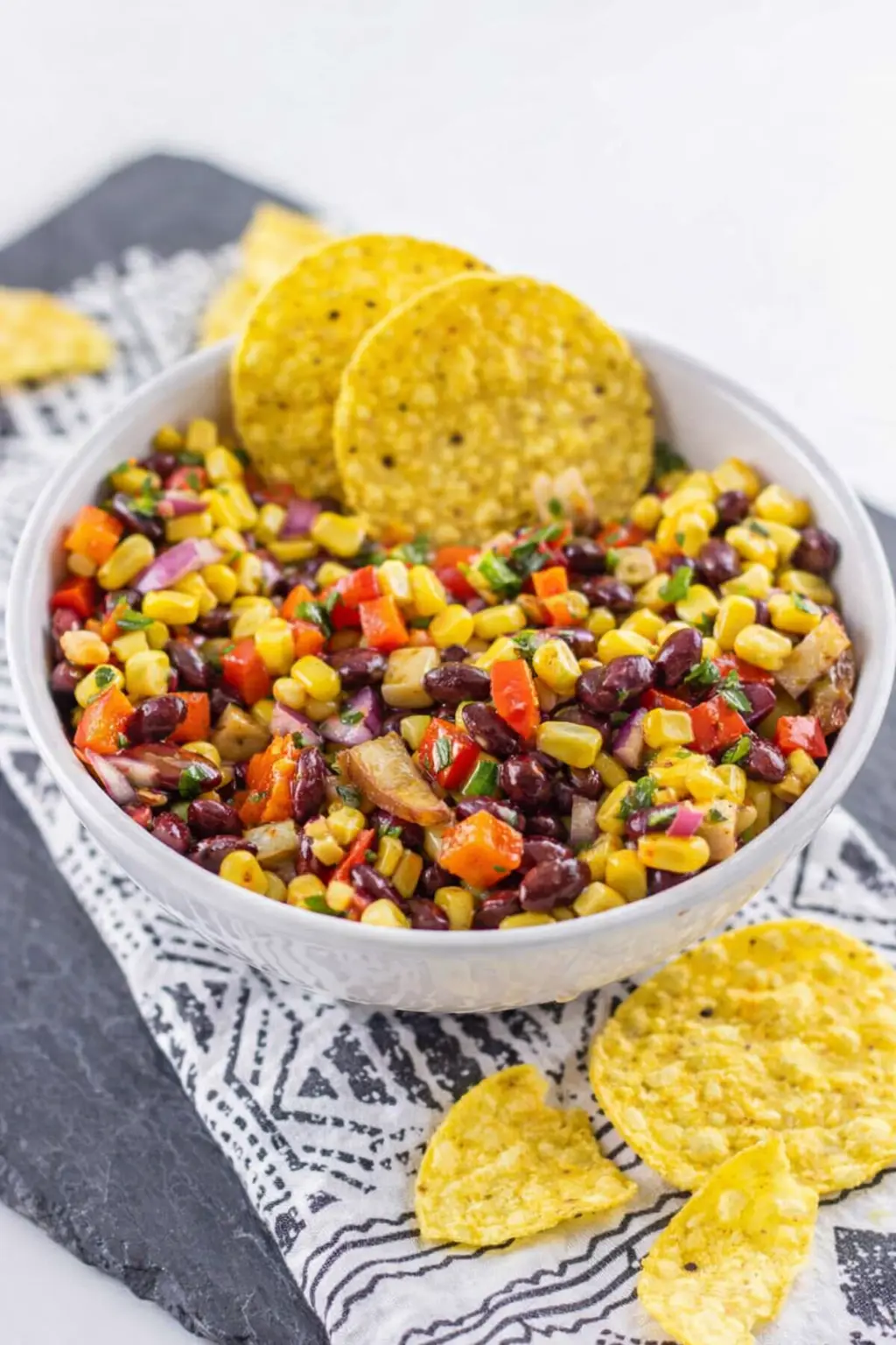 Black bean and corn salsa with tortilla chips in a rustic bowl on a wooden table