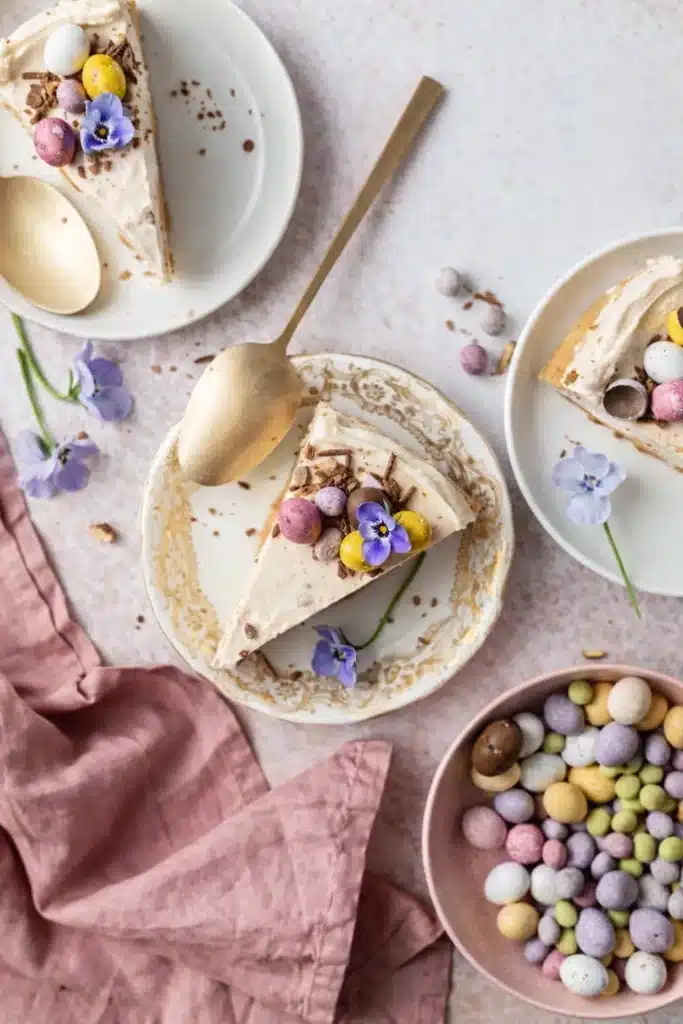 Easter No-Bake Mini Egg Cheesecake slices with pastel chocolate eggs on dessert plates