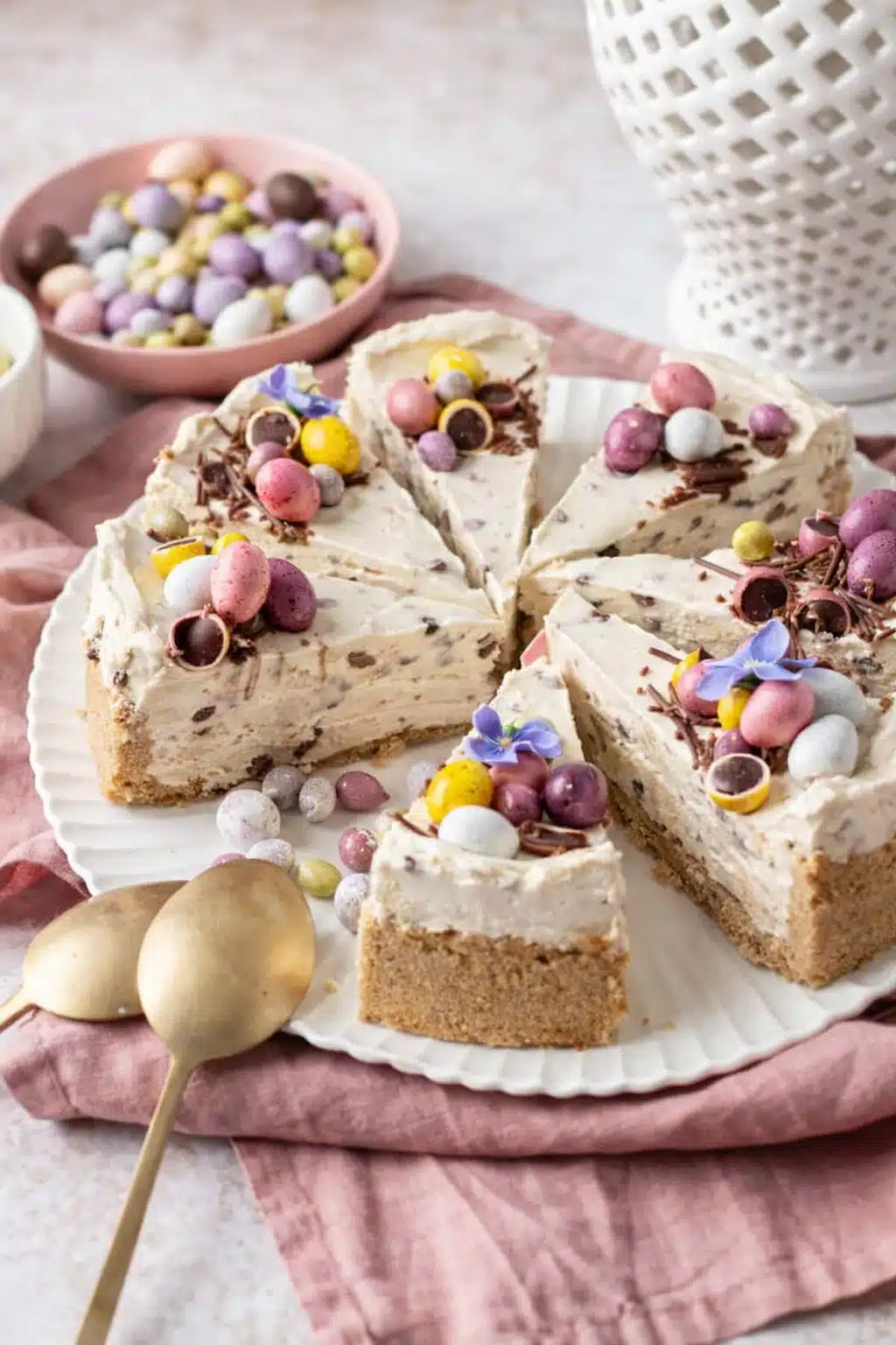 Easter no-bake mini egg cheesecake with pastel chocolate eggs on creamy vanilla cheesecake slices