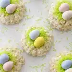 Easy Rice Krispie Easter nests topped with pastel candy eggs and green candy grass on a light background