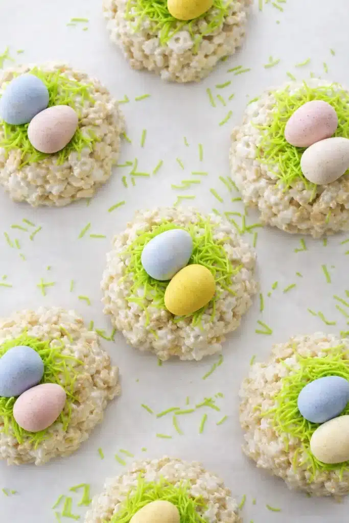 Easy Rice Krispie Easter nests topped with pastel candy eggs and green candy grass on a light background