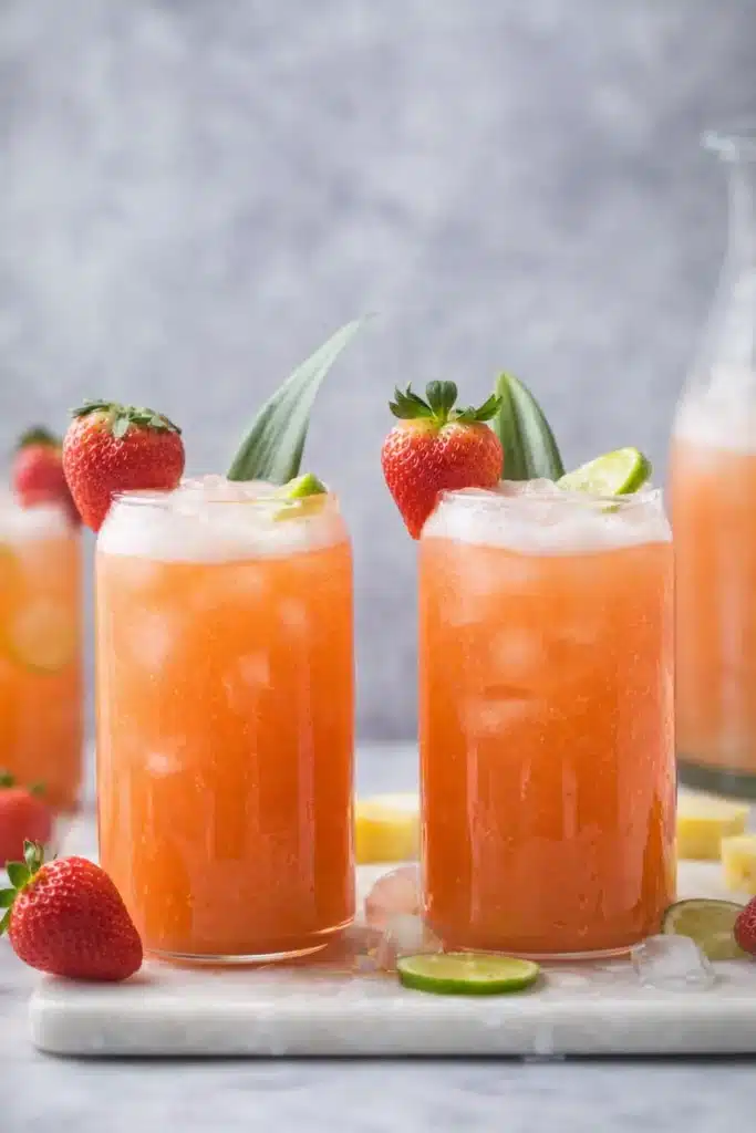 pineapple strawberry agua fresca served in chilled glasses with lime and strawberry garnish