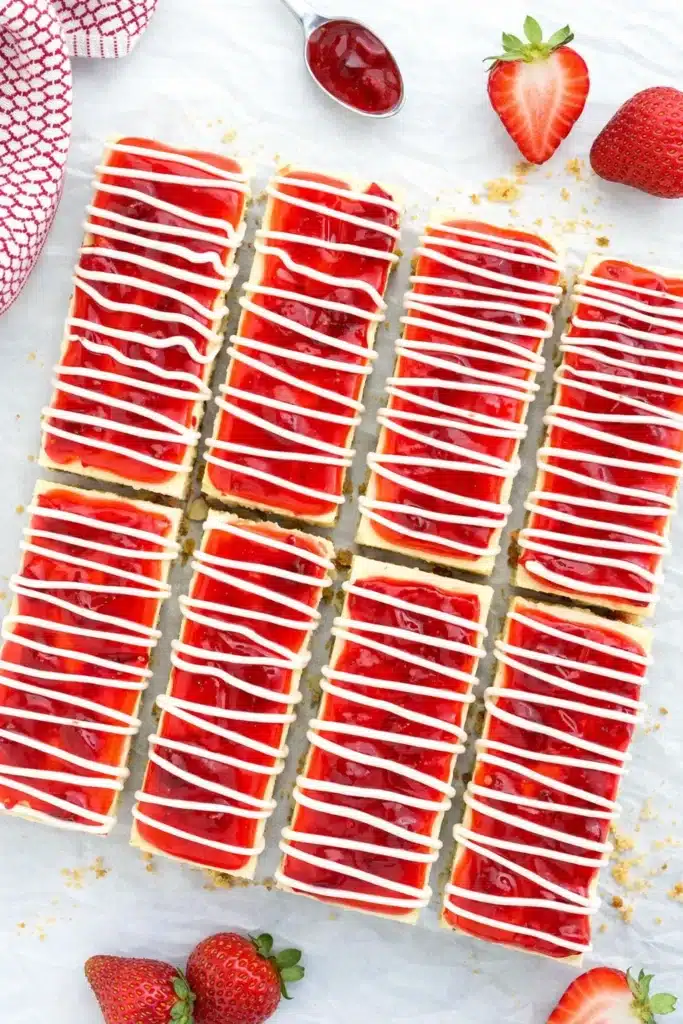 Philadelphia cheesecake bars sliced with strawberry topping and white chocolate drizzle