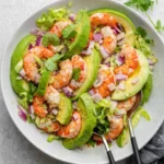 Shrimp avocado salad with lettuce, red onion, and cilantro in a bowl