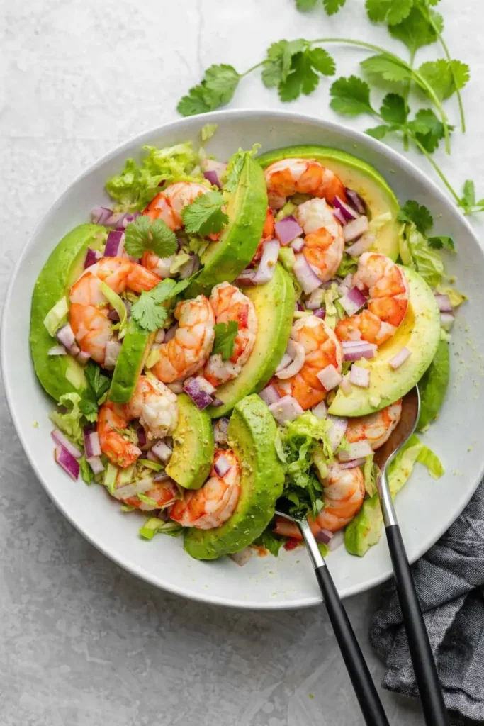 Shrimp avocado salad with lettuce, red onion, and cilantro in a bowl