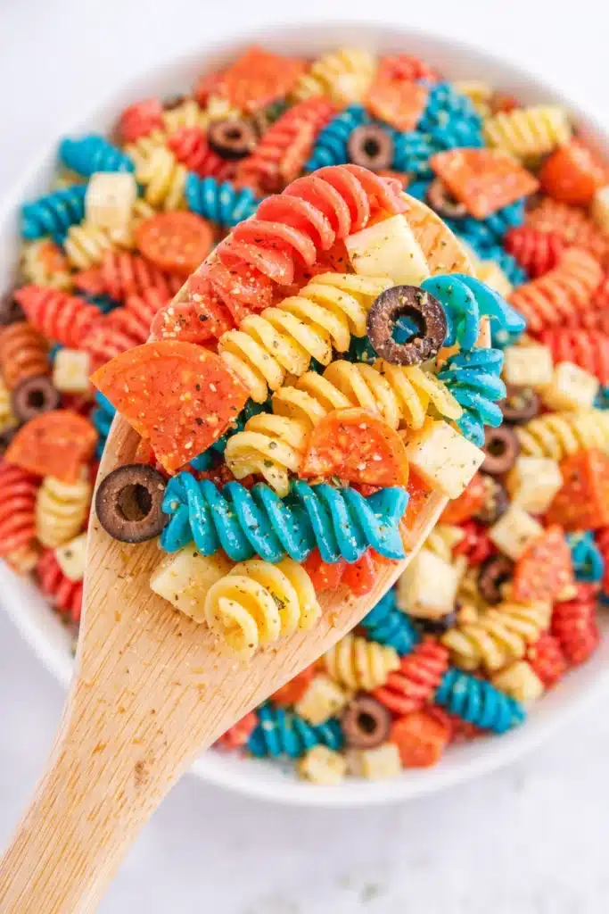 Red White and Blue Pasta Salad on wooden spoon with rotini and mozzarella