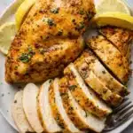Juicy air fryer chicken breast sliced with herbs and lemon on a plate