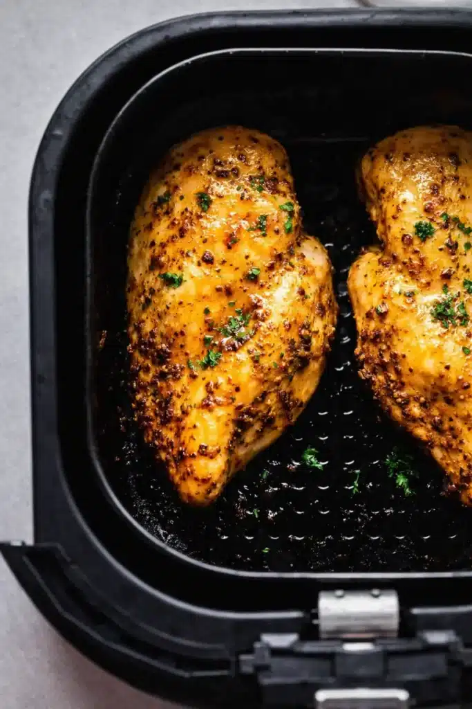 Air Fryer Chicken Breast cooking in basket with golden seasoned crust
