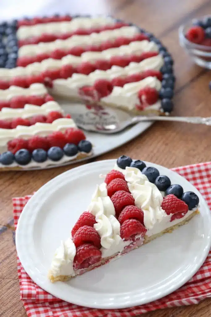Slice of American Flag Fruit Pizza with berries and cream on cookie crust