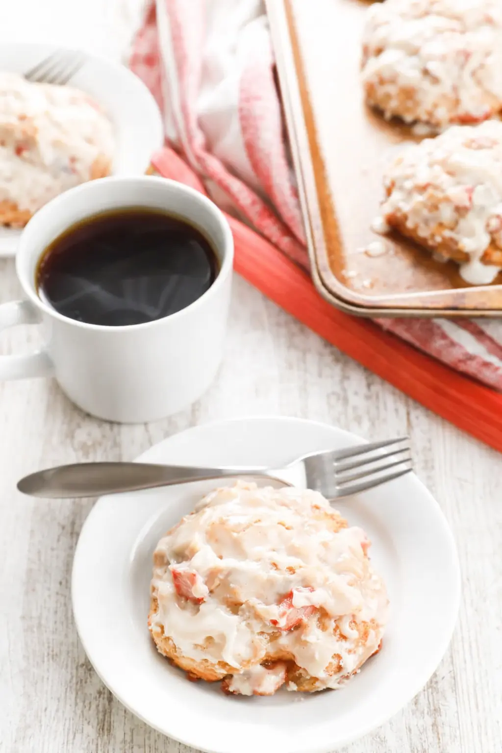 Baked rhubarb fritters with glaze served on plate with coffee