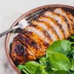Sliced balsamic baked chicken breast with spinach on a plate