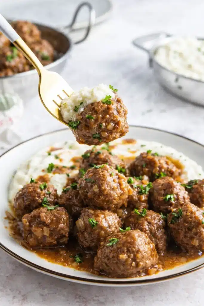 Beefy Onion Crockpot Meatballs Recipe Easy Comfort 5 Beefy Onion Crockpot Meatballs Recipe served over mashed potatoes with fork