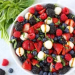Berry caprese salad with fresh berries, mozzarella, basil, and balsamic glaze in a bowl