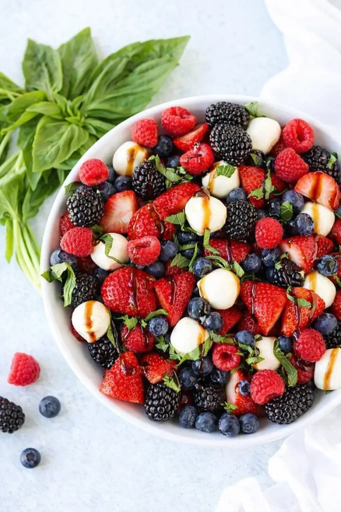 Berry caprese salad with fresh berries, mozzarella, basil, and balsamic glaze in a bowl