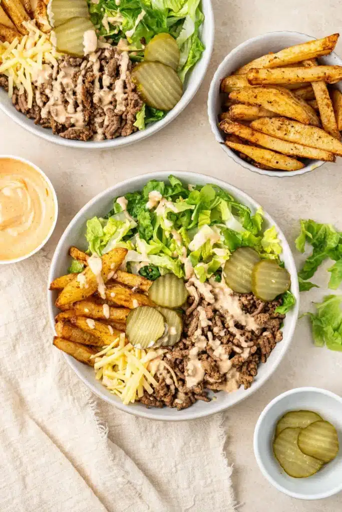 Burger bowls with crispy potatoes, beef, lettuce, pickles, and creamy sauce