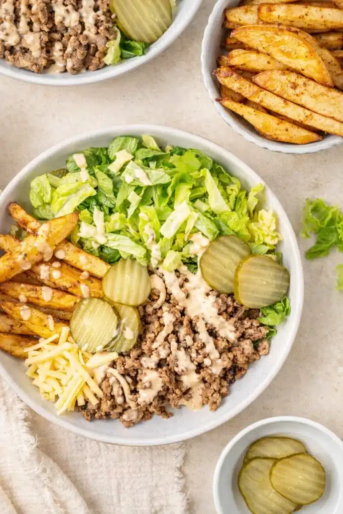 Burger bowls with crispy potatoes, beef, lettuce, pickles, and sauce
