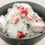 Cheesecake salad with strawberries blueberries and creamy fluff in a bowl