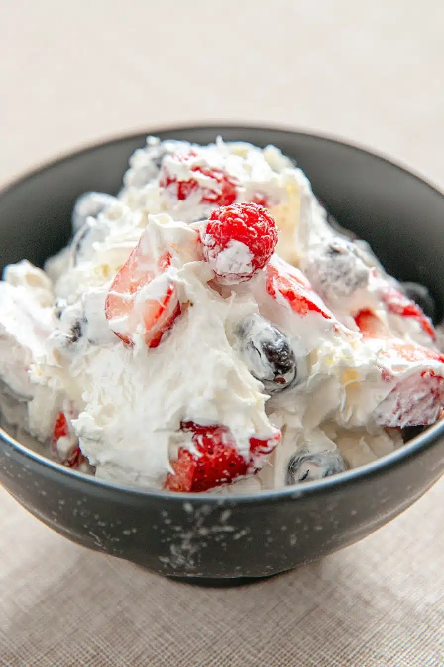 Cheesecake salad with strawberries blueberries and creamy fluff in a bowl
