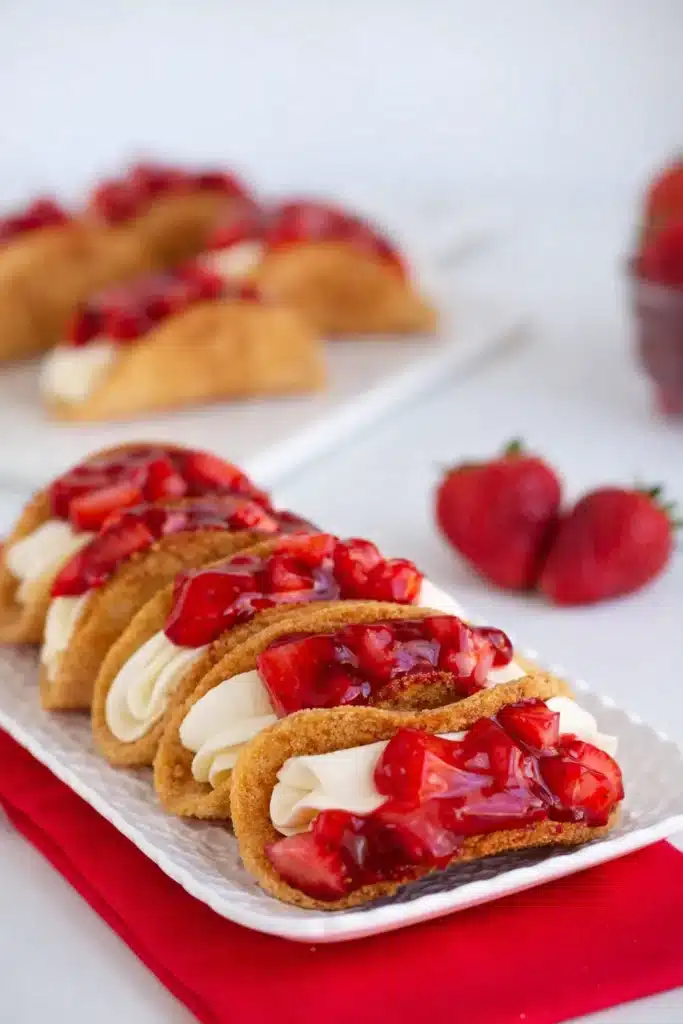 Cheesecake Tacos Easy Amazing Dessert Recipe 5 Cheesecake tacos with strawberry topping and creamy filling on platter