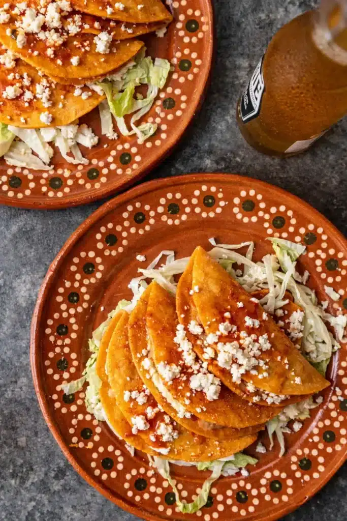 Cheesy Potato Tacos – Crispy, Creamy, and Perfect for Cinco de Mayo 6 Cheesy potato tacos served on rustic plates with salsa, cheese, and lettuce