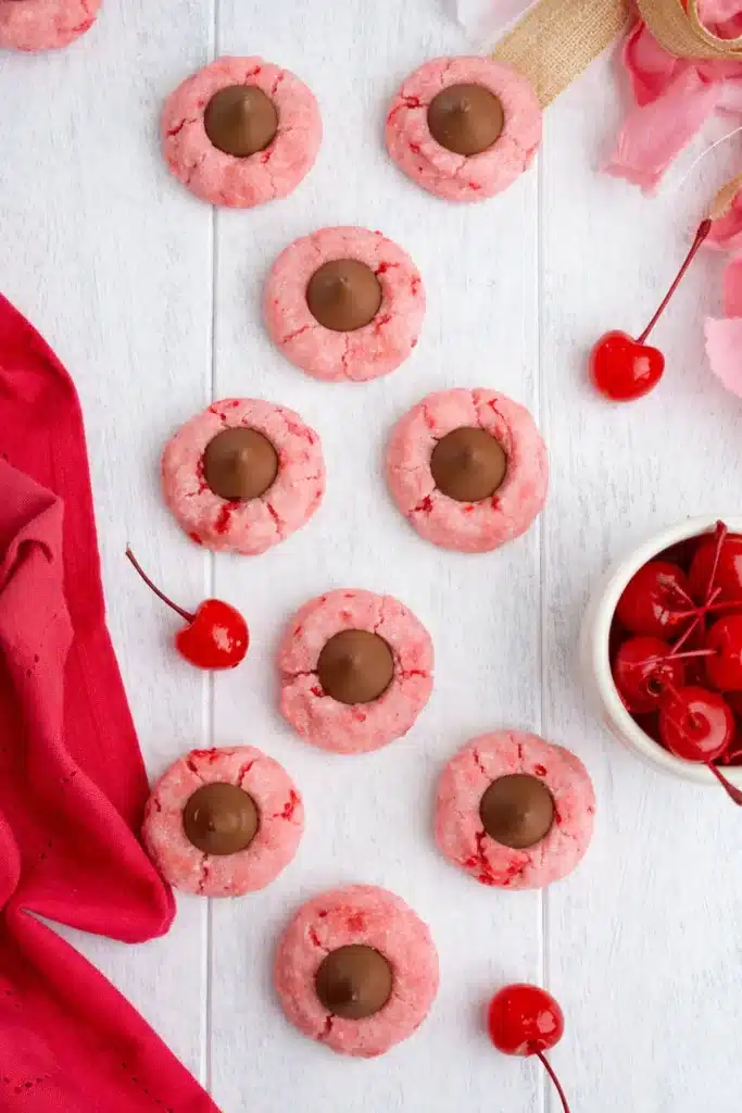 Cherry Blossom Cookies with chocolate centers on white surface with maraschino cherries