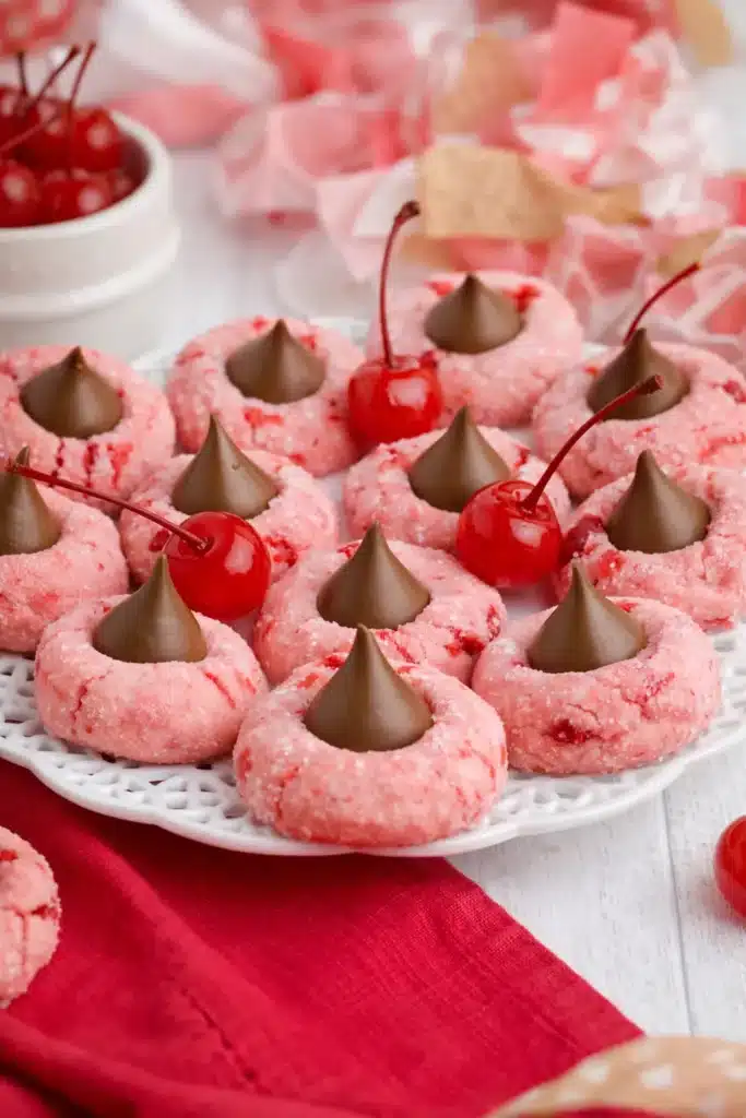 Cherry blossom cookies with chocolate centers and maraschino cherries on white plate