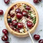 Cherry walnut couscous salad with feta, olives, and fresh herbs in a rustic bowl