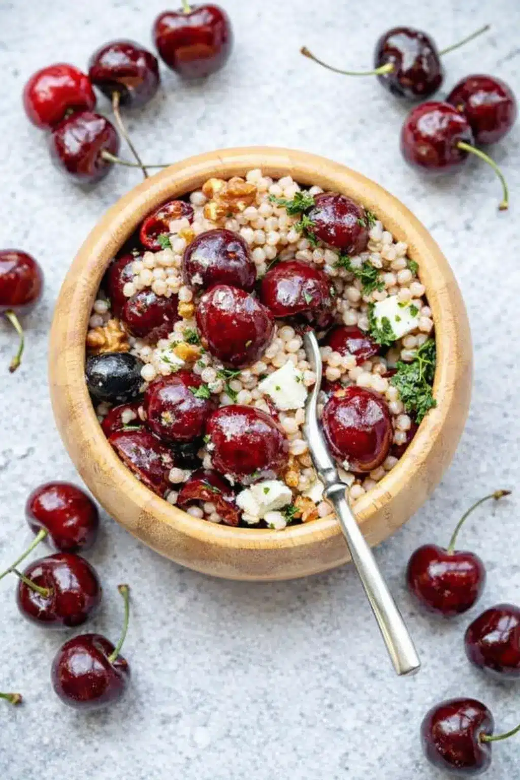 Cherry walnut couscous salad with feta, olives, and fresh herbs in a rustic bowl