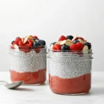 Chia pudding with berry layers and fresh fruit toppings in glass jar