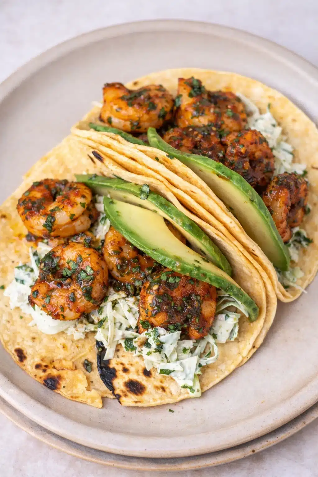 Cilantro lime shrimp tacos with avocado and creamy slaw on corn tortillas