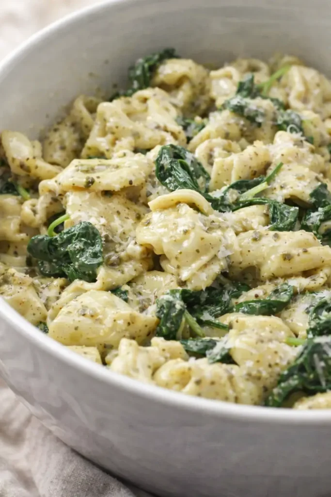 Creamy pesto tortellini with spinach and parmesan in a bowl