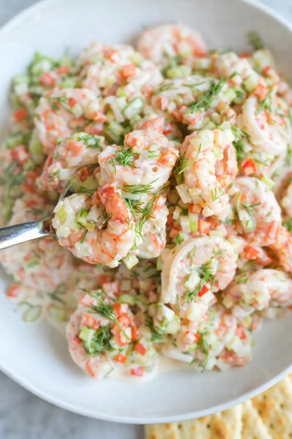 Creamy shrimp salad with fresh dill, celery, and red pepper in a bowl