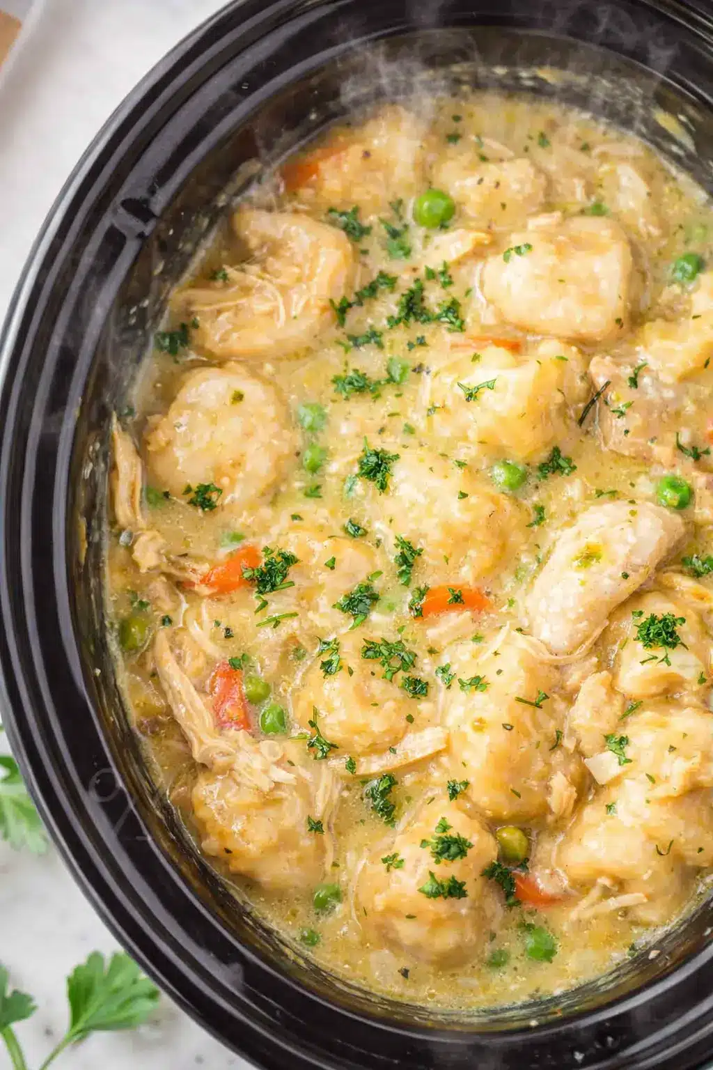 Crockpot chicken and dumplings with creamy broth, fluffy dumplings, peas and carrots