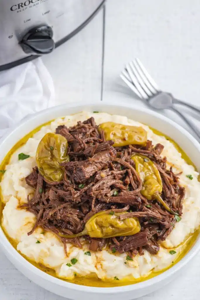 Crockpot Mississippi Pot Roast served over mashed potatoes with peppers