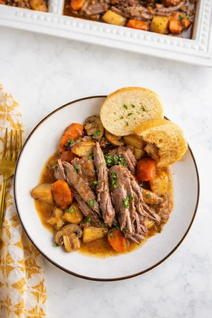 Crockpot Pot Roast Easy Amazing Comfort Recipe 6 Crockpot Pot Roast served with carrots, potatoes, and bread on a plate