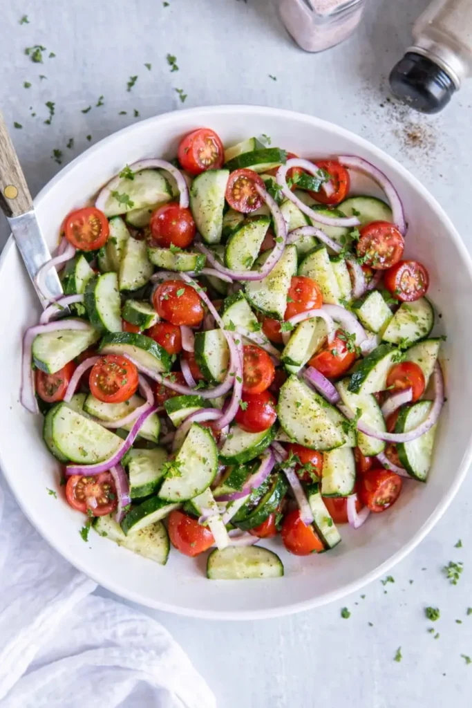Fresh cucumber tomato salad with red onion and herbs in a bowl