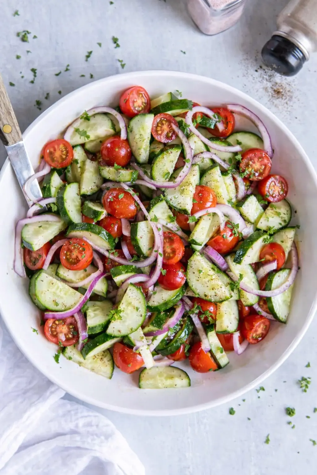 Fresh cucumber tomato salad with red onion and herbs in a bowl