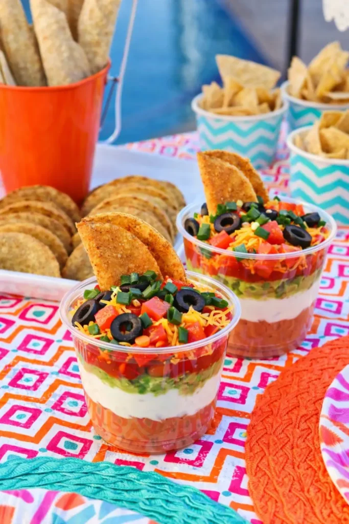 Easy Cinco de Mayo snacks with layered seven layer dip cups and taco shells