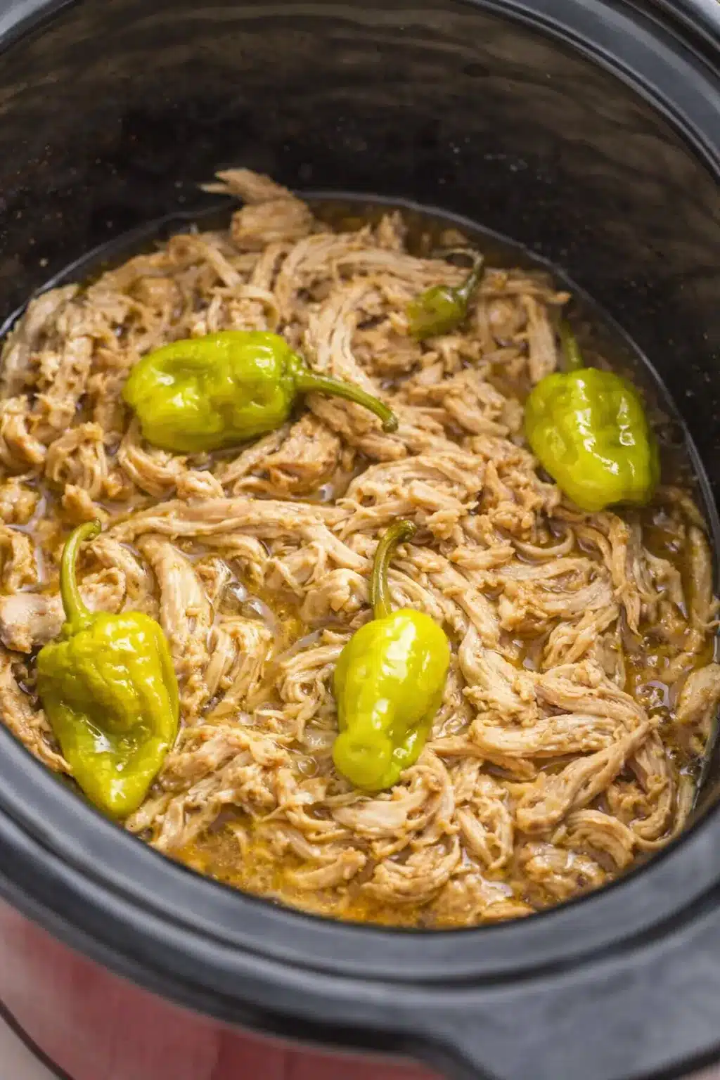 Easy Mississippi chicken with shredded tender meat and pepperoncini peppers in slow cooker