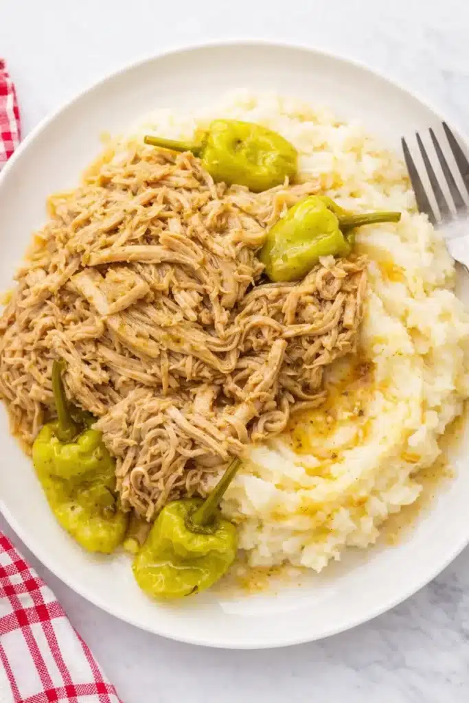 Easy Mississippi Chicken served over mashed potatoes with pepperoncini peppers